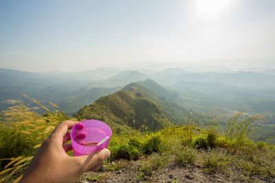 Close-up of hand holding heart shape against mountain