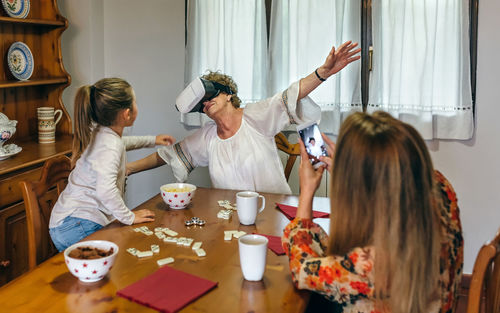 Grandmother with daughter and granddaughter wearing virtual reality simulator at home