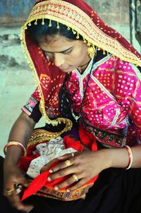 Young woman wearing sari carrying new born at home