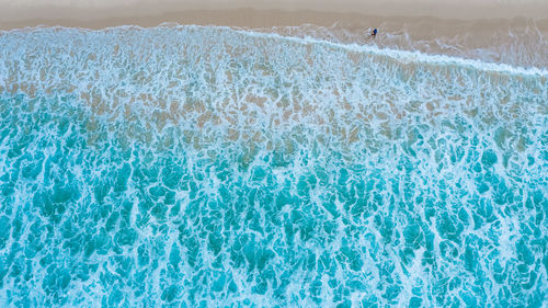 Aerial top view of sandy beach with travelling tourists in beautiful the sea wave 