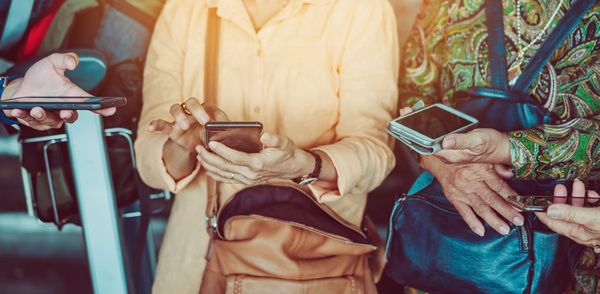 Midsection of people holding mobile phones