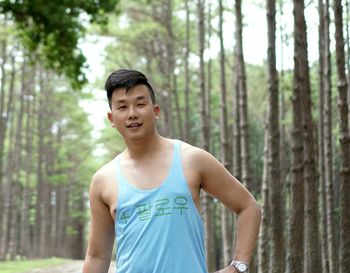 Portrait of handsome mid adult man standing against trees in forest