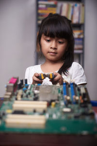 Girl holding mechanical part at home