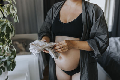 Pregnant woman folding baby clothes and getting ready for baby arrival