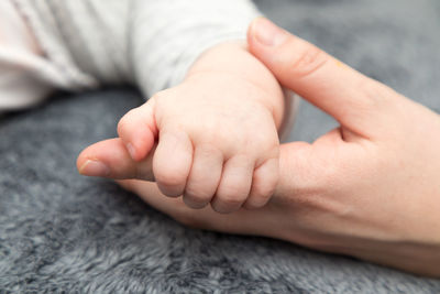 Close-up of baby holding parent on rug at home