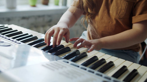 Midsection of girl playing piano