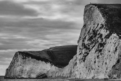 Old ruins on rock by sea against sky