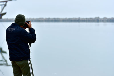 Rear view of man photographing against sky