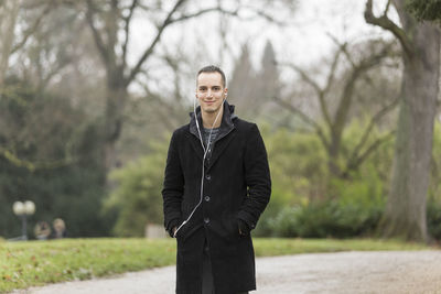 Portrait of young man standing against trees