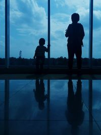 Silhouette people standing by window