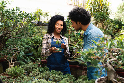 Happy friends standing against plants