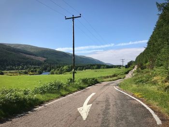 A road running through a green valley with a telegraph pole