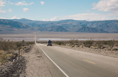 Road by desert against sky