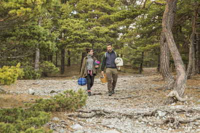 Couple carrying sleeping bags and basket in forest