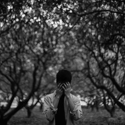 Portrait of man with head in hands in forest