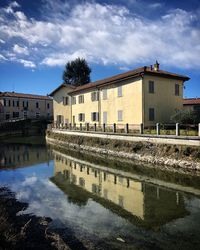 Reflection of building in lake against sky in city