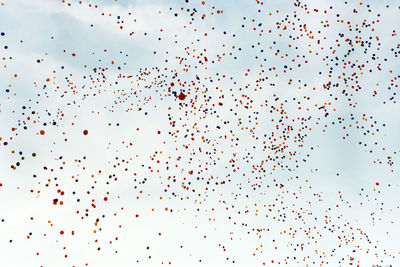 Low angle view of flock of birds flying against sky