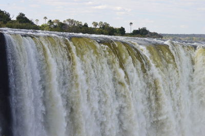 Scenic view of waterfall against sky