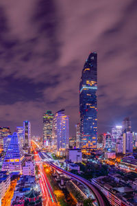 Illuminated modern buildings in city against sky at night