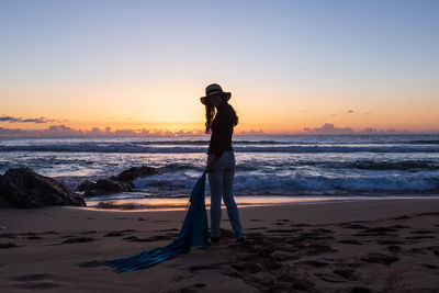 Silhouette of girl with hat at sunset on cotillo beach, fuerteventura, canary islands, handkerchief.