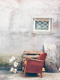 Empty chairs and table against wall of old building