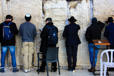 Rear view of men standing against built structure