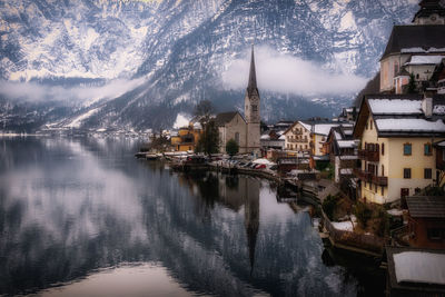 Buildings by sea against mountains during winter