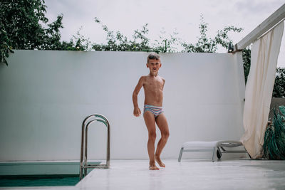 Portrait of shirtless man standing in swimming pool