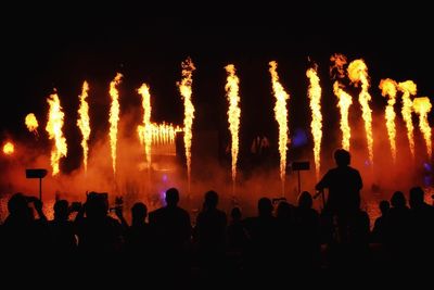 Silhouette people watching at fire against sky at night