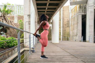 Full length of woman stretching by railing