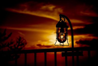Close-up of silhouette lantern against orange sky
