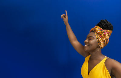 Young woman wearing colorful long clothes over blue background. natural expression.