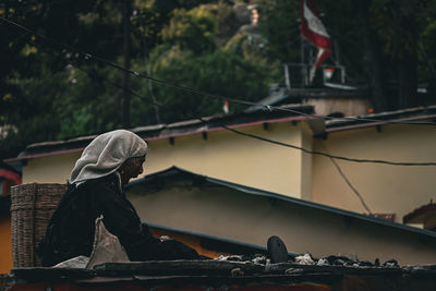 Side view of women sitting on roof of a house