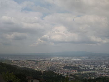 Aerial view of cityscape against cloudy sky