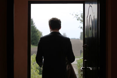 Rear view of man exiting house