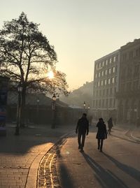 People walking on footpath in city against sky