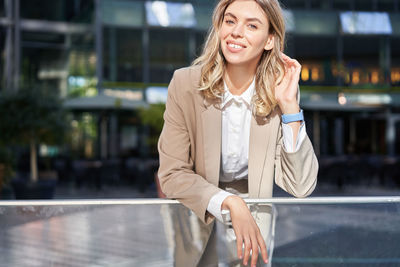 Portrait of young woman standing in city