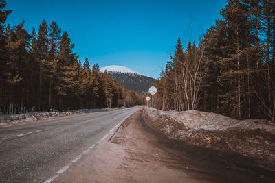 Empty road amidst trees against sky