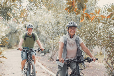 Female friends riding bicycle on field