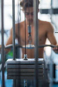 Shirtless teenage boy exercising at gym