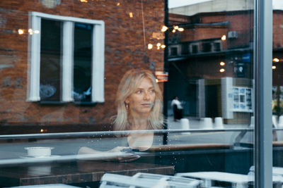 Woman using phone seen through window