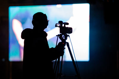 Silhouette man with camera standing in front of screen in studio