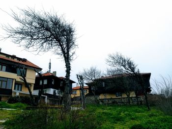 Abandoned house and trees on field against clear sky