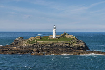 Lighthouse by sea against sky