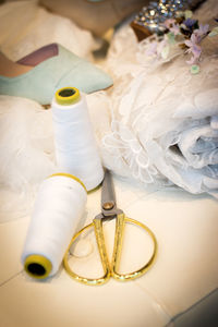 Close-up of shoes and spools with wedding dress