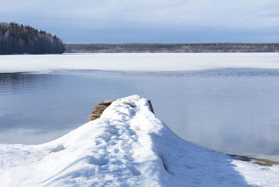 A pier in the snow on the lake. melting of ice on the lake in early spring. calm serenity nature.