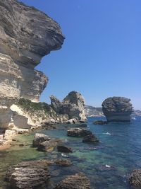 Scenic view of rocks in sea against clear blue sky - bonifacio, corsica