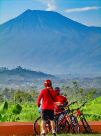 Rear view of man bicycling on landscape against sky