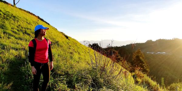 Smiling young woman hiking on mountain during sunny day