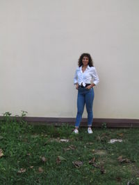 Portrait of young woman standing against wall